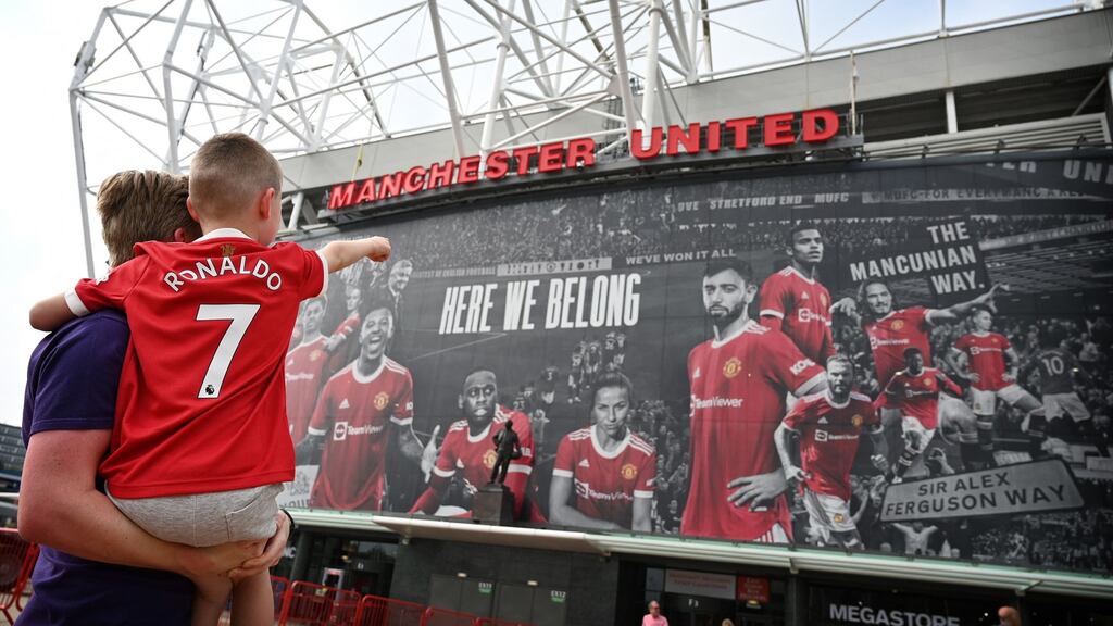 A young fan wearing the shirt of Manchester United’s new signing Cristiano Ronaldo points to Old Trafford. Photo: Paul Ellis/AFP via Getty Images