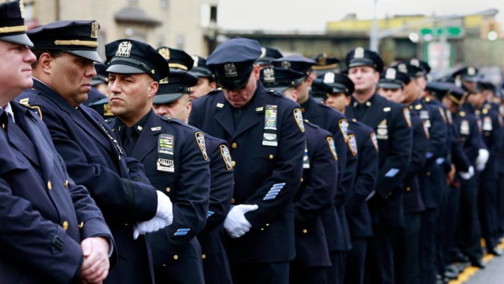 Police officers stand, with some turning their backs, as New York City mayor Bill de Blasio speaks at the funeral for officer Wenjian Liu in Brooklyn. Photograph: Reuters