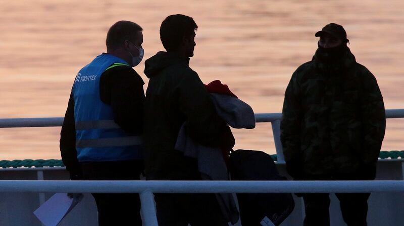 A migrant (centre) is escorted by a Frontex officer (left) into a ferry in the port of Mytilene, Lesvos Island, on Monday. Photograph: EPA