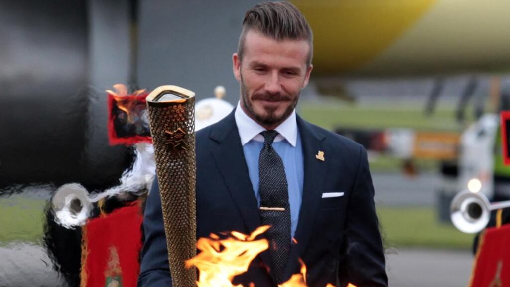 David Beckham holds the Olympic flame in London – we find out today which city will host in 2020. Photograph: Getty.