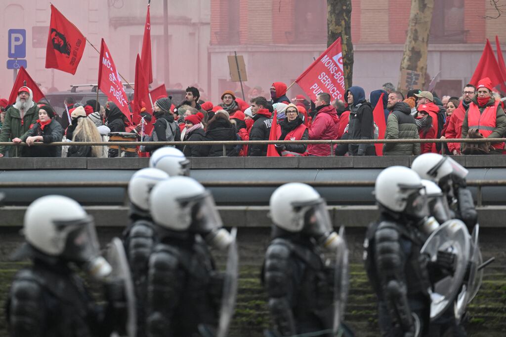 Demonstrators  walk past police officers in riot gear during a nationwide protest called by  unions against the new government's plan to reform special pension schemes. Photograph:  Nicolas Tucat/AFP via Getty Images