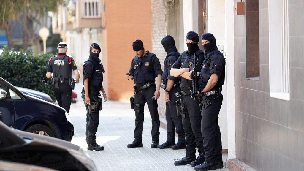 Several Mossos d’Esquadra officers stand guard outside the residential building where the man lived in the town Cornella de Llobregat, in Barcelona. Photograph: EPA/Enric Fontcuberta