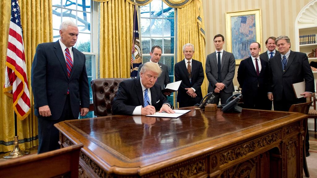 US president Donald Trump, surrounded by aides, signs the first of three executive orders in the Oval Office at the White House on Monday.  Photograph: EPA/Ron Sachs