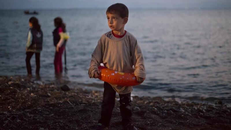 A Syrian migrant boy still wearing a swimming ring stands on the beach upon his arrival with other migrants by a dinghy at the southeastern Greek island of Kos early today. Photograph: Alexander Zemlianichenko/AP