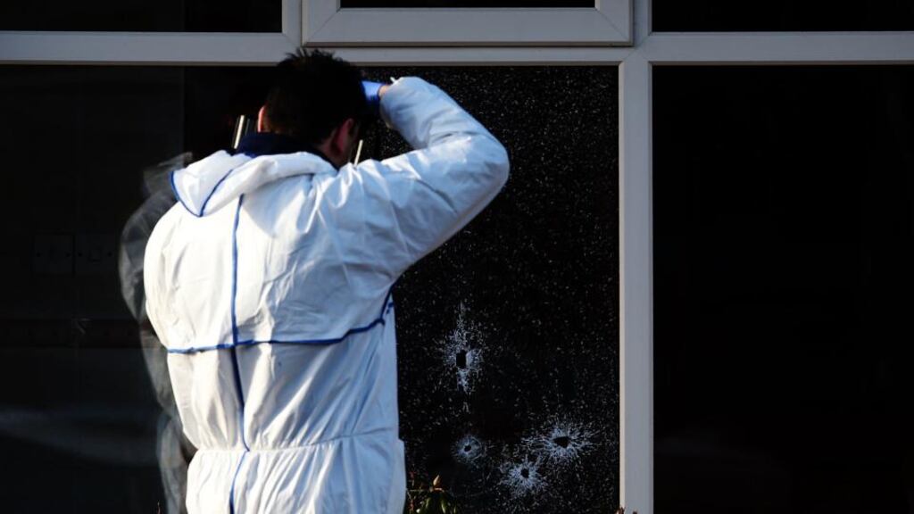 A member of the Garda forensics team photographs bullet holes at the house on Harty Avenue in Walkinstown where Eddie Nugent (64) was murdered. Photograph: Brian Lawless/PA Wire.