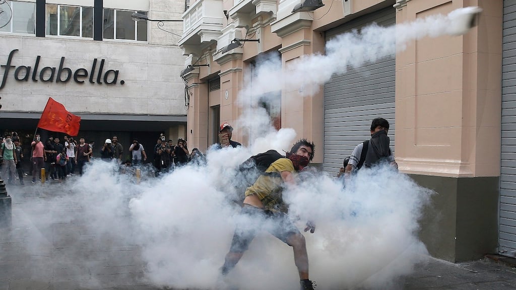A demonstrators throws a tear gas canister back towards police during clashes after the pardoning of former president Alberto Fujimori in Lima, Peru. Photograph: Martin Mejia/AP Photo