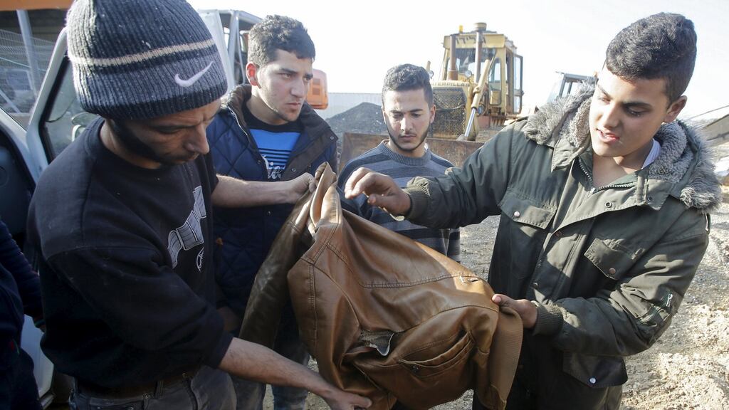 Bystanders check the jacket of a Palestinian killed by Israeli soldiers near where the Israeli military said another Palestinian had tried to stab a soldier in the West Bank city of Hebron, January 12th, 2016. Photograph: Mussa Qawasma/Reuters