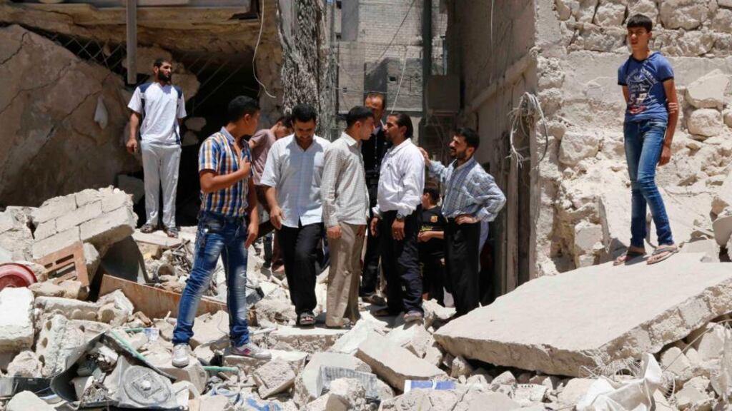 People stand amid rubble of collapsed buildings at a site hit by what activists said was a barrel bomb dropped by forces loyal to Syria’s president Bashar al-Assad in the Al-Fardous neighbourhood of Aleppo yesterday. Another bomb has killed at least eight people in Mayadeen today. Photograph: Hosam Katan/Reuters