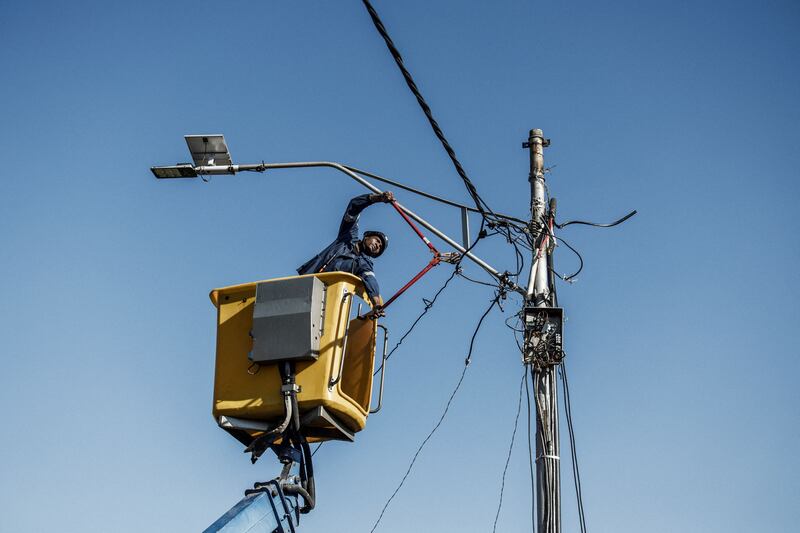 A City Power worker uses wire cutter to cut and remove an illegally connected electrical cable used by residents of an informal settlement in the Brixton area of Johannesburg to connect to the electrical grid on June 9th, 2022 during an operation patrolled by South African Police Services (SAPS) officers. Photograph: Marco Longari/AFP via Getty Images