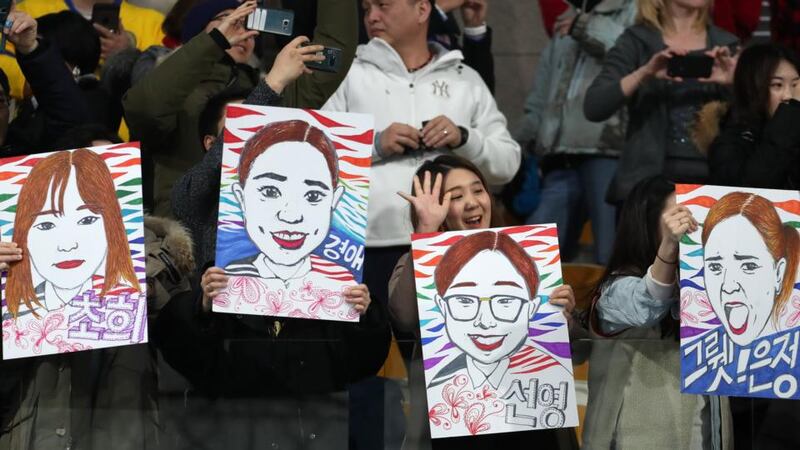 Fans of South Korea hold portraits of their team’s players during the women’s curling gold medal match against Sweden. Photograph: Javier Etxezarreta/EPA