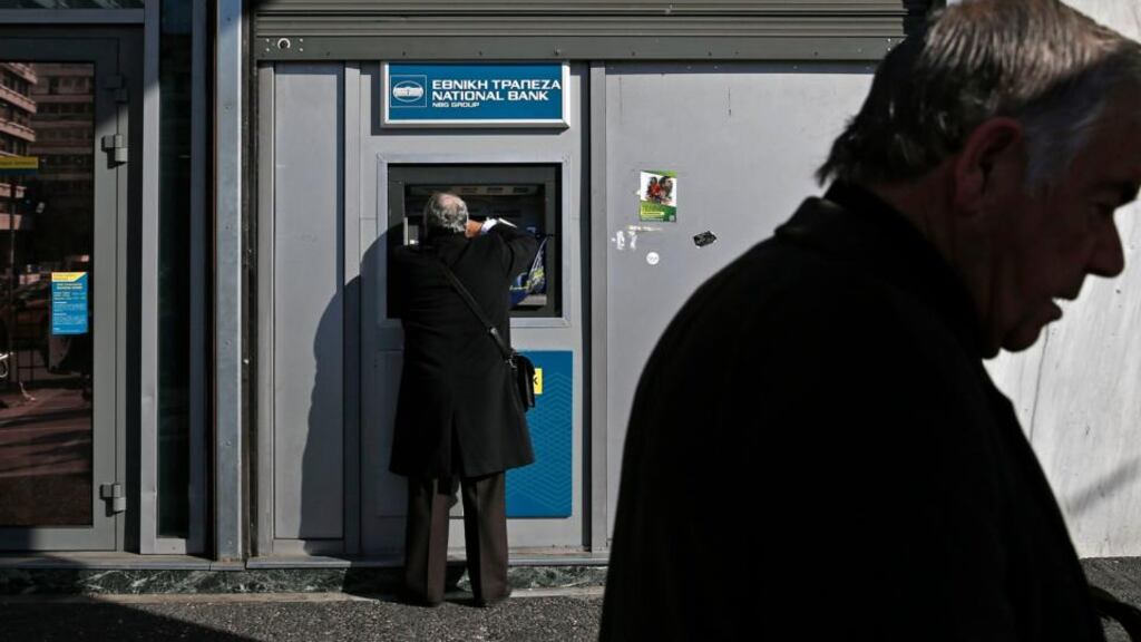 A man makes a transaction at an ATM outside a National Bank of Greece branch in Athens, on Thursday. Photograph: Alkis Konstantinidis/Reuters