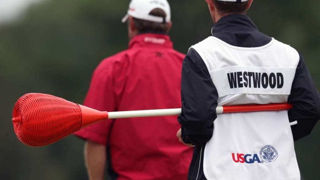 Lee Westwood’s caddie holds the one of the unique Merion pins topped with wicker baskets in place of the usual flags during the first round of the US Open at the Merion Golf Club in Ardmore, Pa. Photo: Doug Mills/The New York Times)