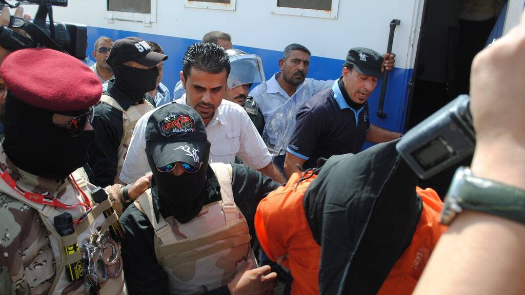 Iraqi security forces escort a man  sentenced to death over the mass killing of hundreds of mainly Shia soldiers at a former US base  two years ago: A local official criticised the executions saying some of the men   had been tortured to extract confessions. Photograph:  Stringer/Reuters