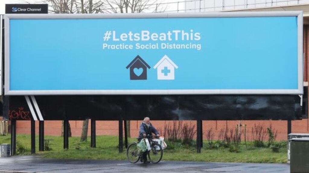 A man passes by a sign in Belfast urging the public to practise social distancing, as the coronavirus outbreak continues. File photograph: Niall Carson/PA Wire