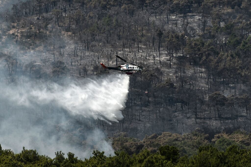 A firefighting helicopter drops water over a wildfire spreading near the village of Lefkimmi, in Greece, in September 2023. Photograph: Sakis Mitrolidis/Getty Images