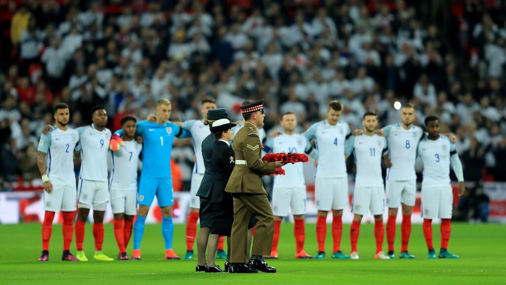 Members of the British armed services carry a poppy wreath onto the pitch as England players look on in remembrance of Armistice Day prior to the World Cup qualifying match between England and Scotland at Wembley Stadium. Photograph: Richard Heathcote/Getty Images