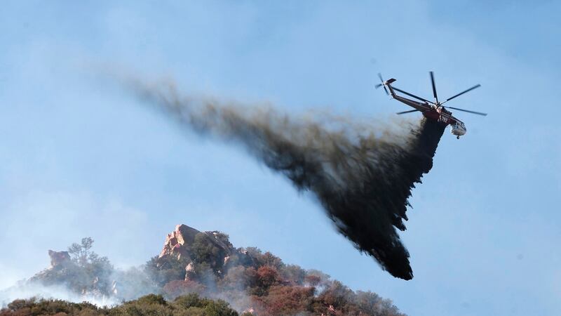 A helicopter drops water on brush burning near Pepperdine University in an attempt to tackle the Woosley Fire in Malibu, California. Photograph: Mike Nelson/EPA