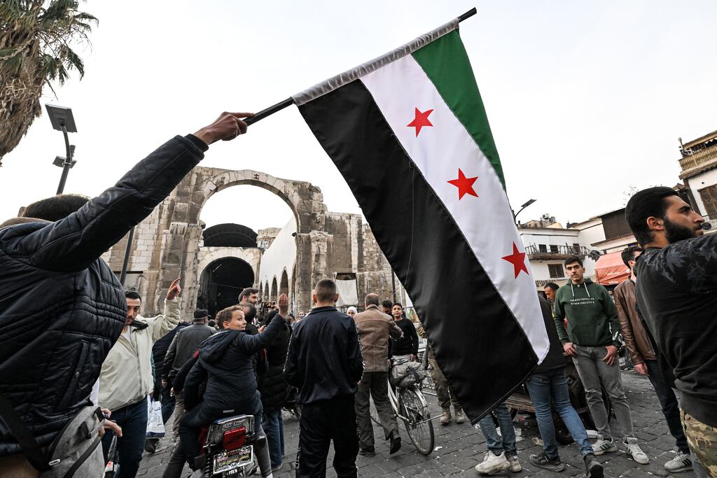 A man holds a flag of the Syrian opposition near the entrance of the Hamidiyah covered market in the old part of Damascus on December 10th. Photograph: Louai Beshara/AFP via Getty