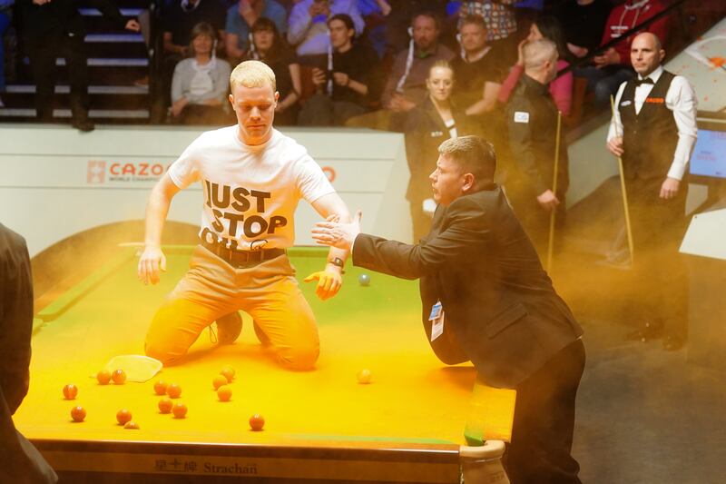 A Just Stop Oil protester is removed after jumping on the snooker table and throwing orange powder during the match between Robert Milkins and Joe Perry at the Crucible Theatre, Sheffield, last April. Photograph: Mike Egerton