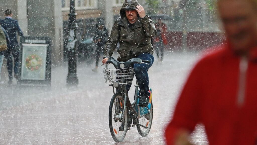 People seek cover amid the heavy showers in Dublin on Tuesday afternoon.  Photograph: Nick Bradshaw/The Irish Times