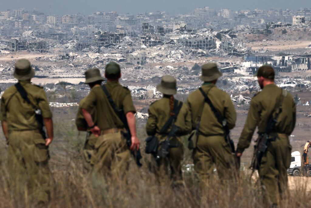 Israeli soldiers look at destroyed buildings in the Gaza Strip as they stand on the border with the Palestinian territory. Photograph: Jack Guez/AFP via Getty Images