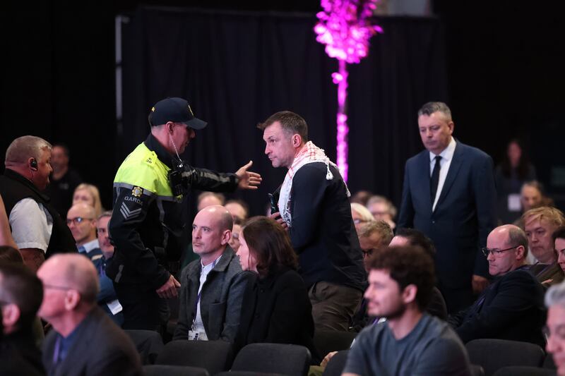 A protester is escorted out from the RIAI conference by a gardaí. Photograph: Dara Mac Dónaill/ The Irish Times