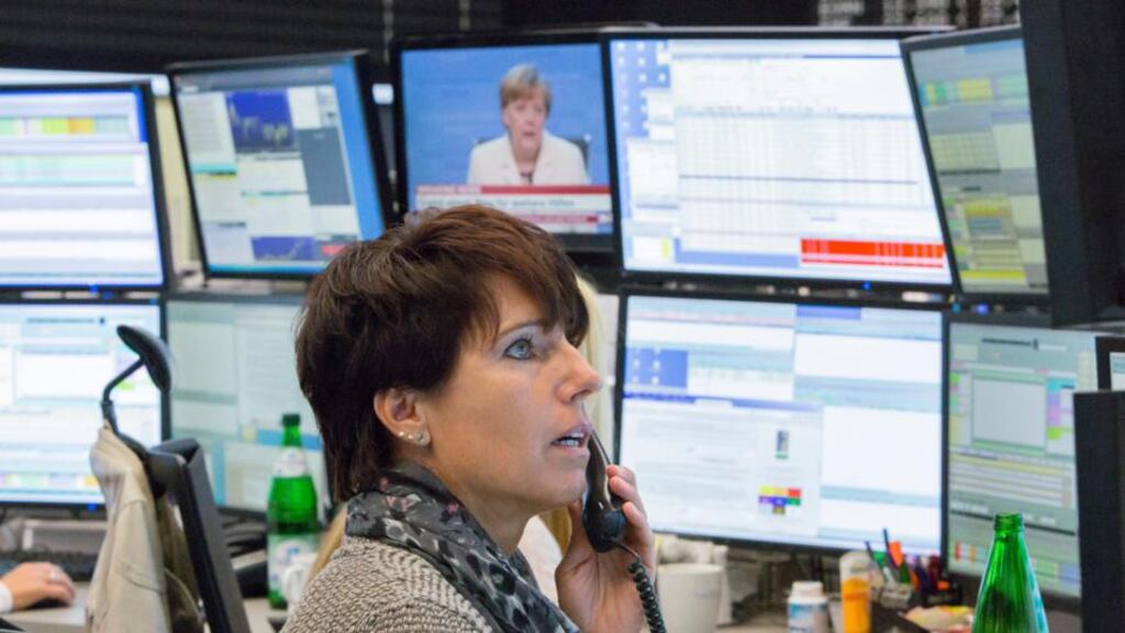 A television screen shows Angela Merkel, Germany’s chancellor, speaking during a Greek bailout news report as a trader monitors financial data inside the Frankfurt Stock Exchange in Frankfurt, Germany, yesterday. Photographer: Martin Leissl/Bloomberg
