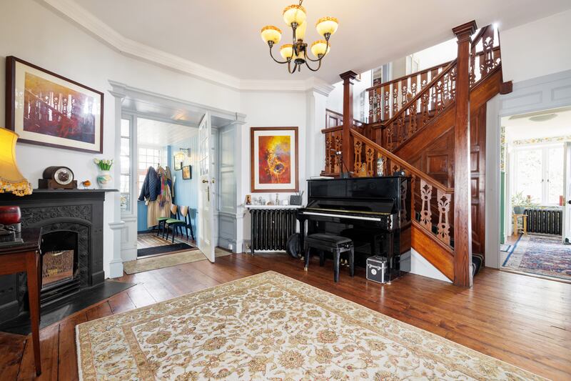 A large hallway has a fireplace and an impressive panelled staircase