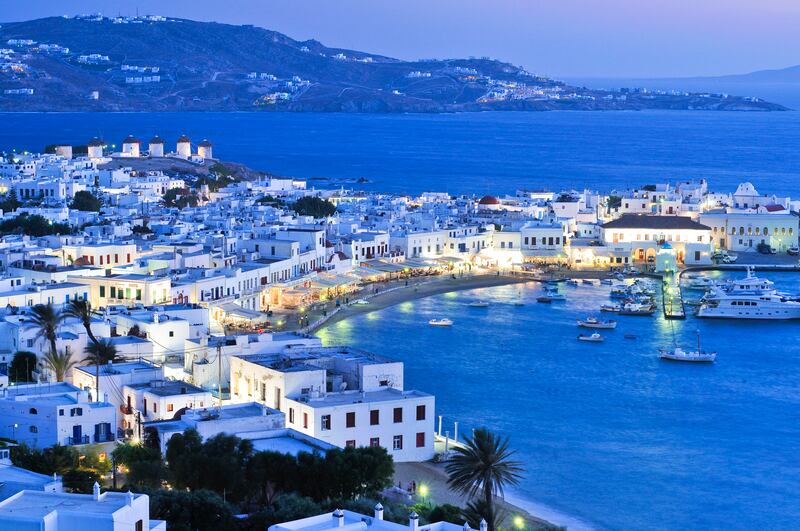 Mykonos harbour in the evening, the island's famous windmills visible at the left