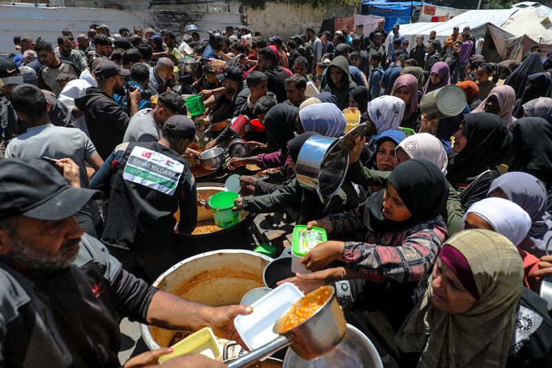Hungry, dislocated Palestinians rush to a food distribution kitchen in Gaza. Photograph: Moiz Salhi/Middle East Images/AFP via Getty