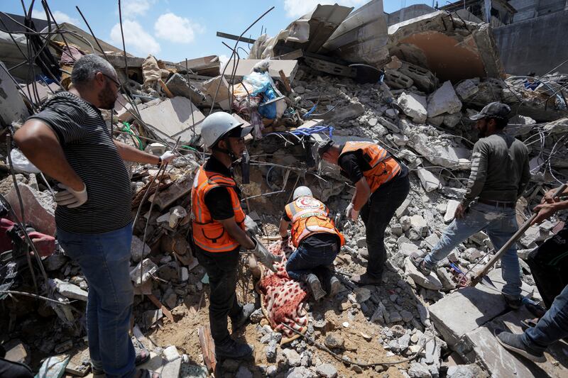 Palestinians rescuers digging around the body of a man in the rubble of a building destroyed in an Israeli airstrike in Nuseirat, Gaza Photograph: AP