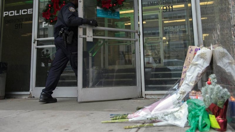 A police officer walks into the 84 Precinct, past a makeshift memorial for two police officers who were fatally shot, in the Brooklyn borough of New York. Photograph: Stephanie Keith/Reuters.