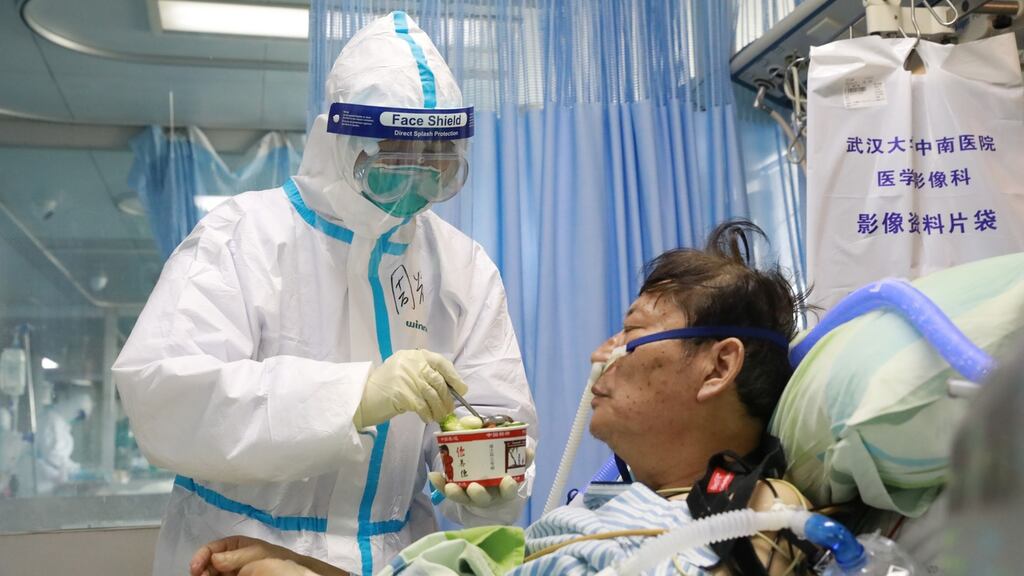 A nurse in a protective suit feeds a novel coronavirus patient inside an isolated ward at Zhongnan Hospital of Wuhan University. Photograph: China Daily via Reuters