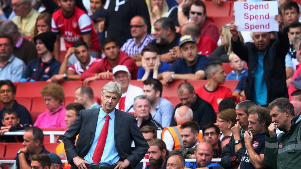 Arsene Wenger of Arsenal looks on as a fan behind makes his feelings known. Photograph: Clive Mason/Getty Images