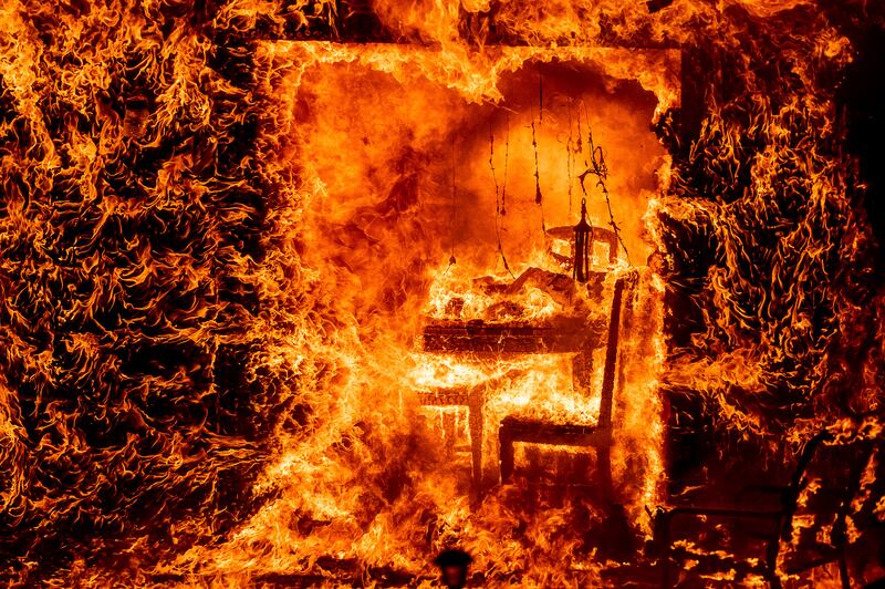 Flames engulf a chair inside a burning home as the Oak Fire burns in Mariposa County .