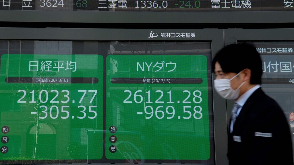 A pedestrian walks past quotation boards displaying a share price from the Tokyo Stock Exchange. Photograph: Kazuhiro Nogi/AFP