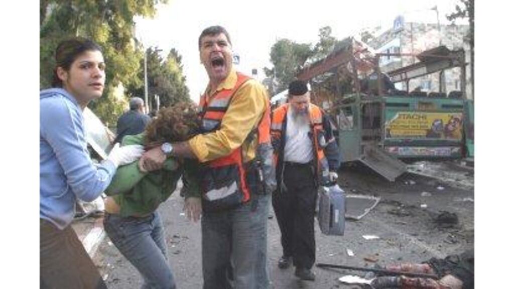 The injured receive aid next to the wreckage of a bus yesterday after a suicide bombing near Mr Ariel Sharon’s official residence.