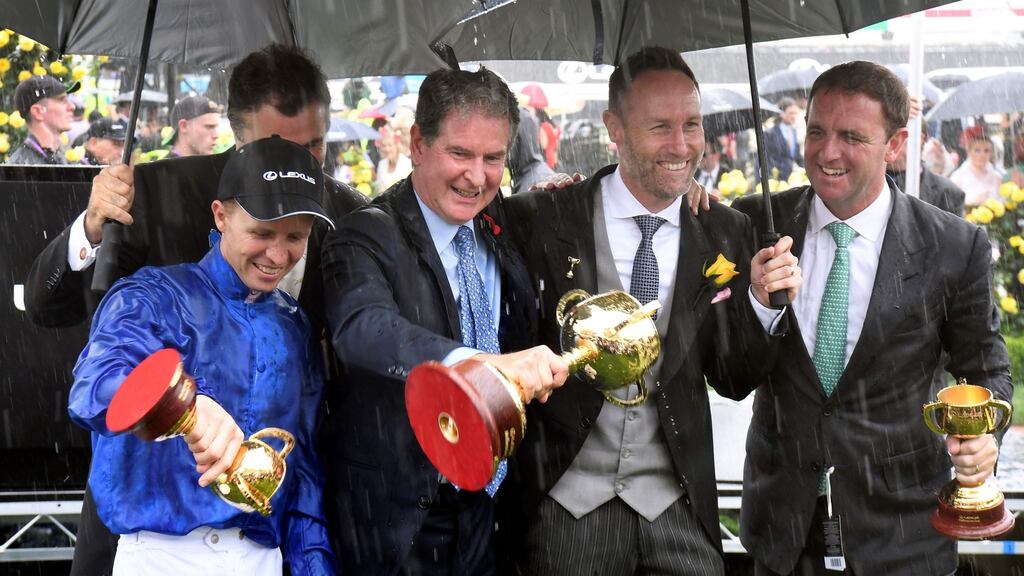 Jockey Kerrin McEvoy and Godolphin CEO Hugh Anderson pour water from the trophies as they celebrate with Lexus CEO Scott Thompson and trainer Charlie Appleby in the mounting yard after winning the Melbourne Cup with Cross Counter. Photo: William West/Getty Images