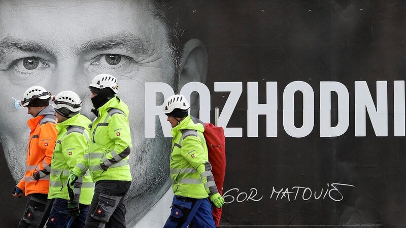 Workers walk past an election poster of Ordinary People and Independent Personalities leader Igor Matovic, ahead of the country’s parliamentary election, in Bratislava. The poster reads: “Decide”. Photograph: David Cerny/Reuters