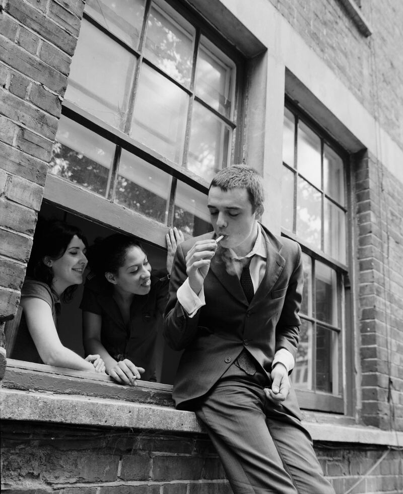 Two women watch from a window as Pete Doherty lights a cigarette, in 2003. Photograph: Andy Willsher/Redferns/Getty Images