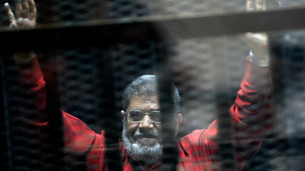 Former Egyptian president Mohammed Morsi raises his hands inside a defendants cage in a makeshift courtroom at the national police academy, in Cairo. Photograph: Ahmed Omar/AP Photo