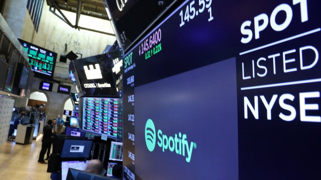 A screen displays the company logo and trading info for Spotify on the floor at the New York Stock Exchange (NYSE)