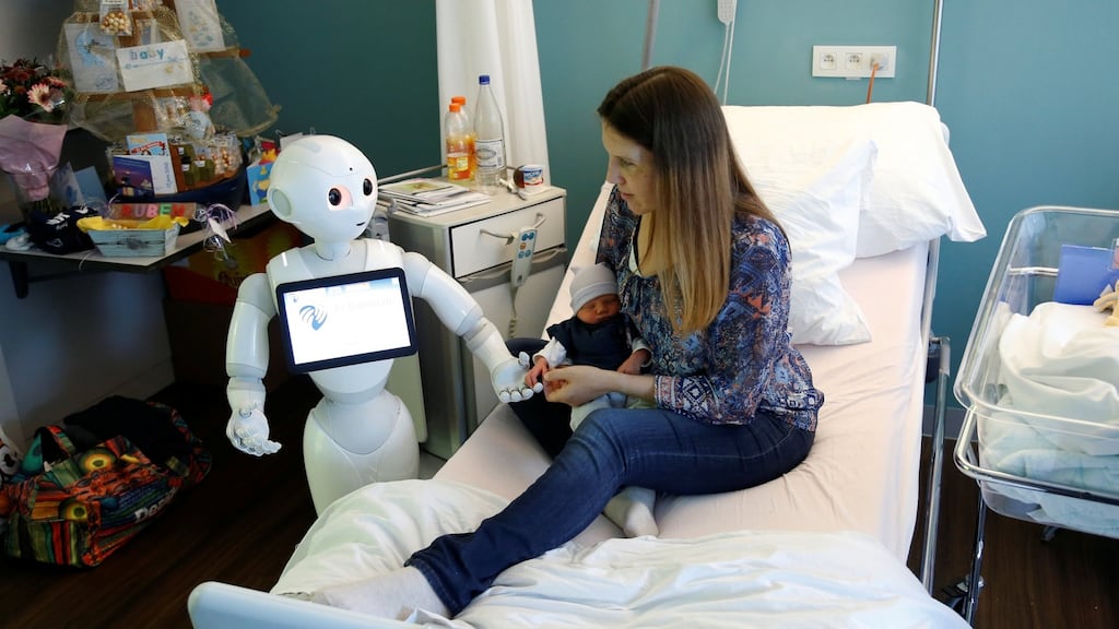 New recruit “Pepper” the robot, a humanoid robot designed to welcome and take care of visitors and patients, holds the hand of a new born baby next to his mother at AZ Damiaan hospital in Ostend, Belgium. Photograph: REUTERS/Francois Lenoir