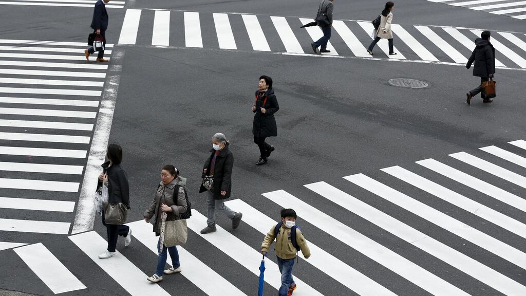 People cross a street in the Ginza shopping district in Tokyo, Japan, March 24, 2016. Japan’s consumer inflation was flat in the year to February, new figures show