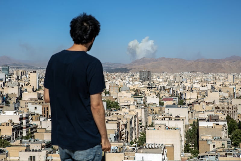 A man in Tehran watches as smoke billows into the air during an Israeli air strike on Wednesday. Photograph: Arash Khamooshi/ The New York Times