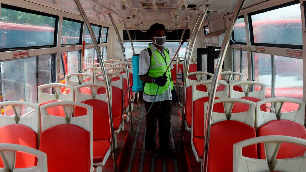 A Inidan worker sanitises a public bus.