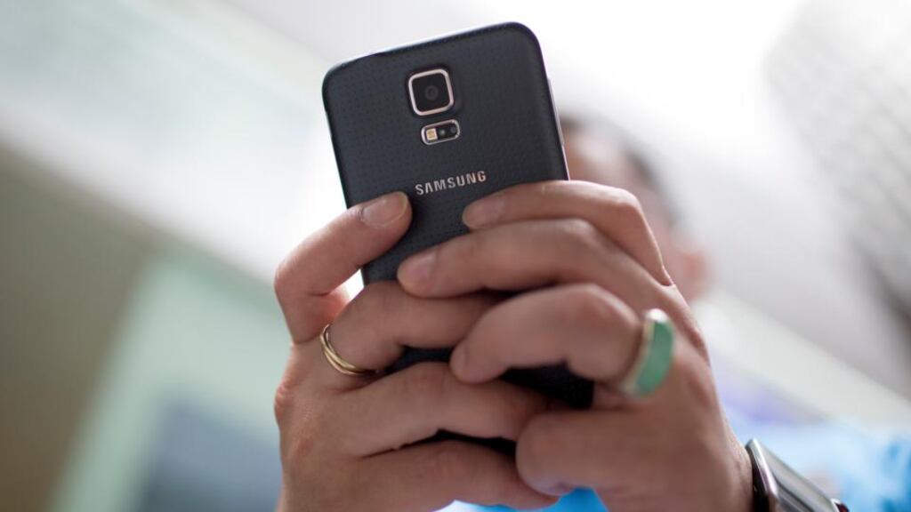 A man holds a Samsung Electronics Co. Galaxy S5 smartphone in an arranged photograph outside a Samsung retail store in the Central district of Hong Kong, China. Photographer: Brent Lewin/Bloomberg