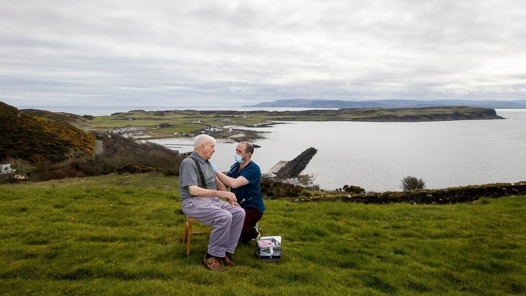 Dr Gavin Chestnutt vaccinates Duncan Smythe (92) in his front garden overlooking the Rathlin Island coastline, Northern Ireland. Photograph: www.thisisjude.uk, Glenn Edward, Liam McBurney and the NHS/PA Wire