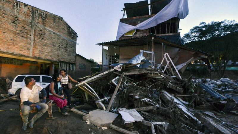 A family wait outside their home damaged by mudslides following heavy rains in Mocoa, Putumayo department, southern Colombia on Saturday. Photograph: AFP/Getty Images