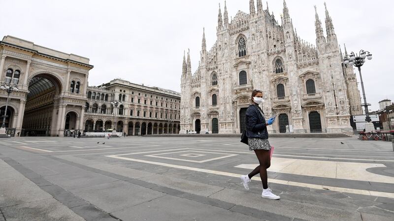 A tourist wearing a protective face mask walks in Piazza Duomo in Milan. Photograph: EPA/ Daniel Dal Zennaro